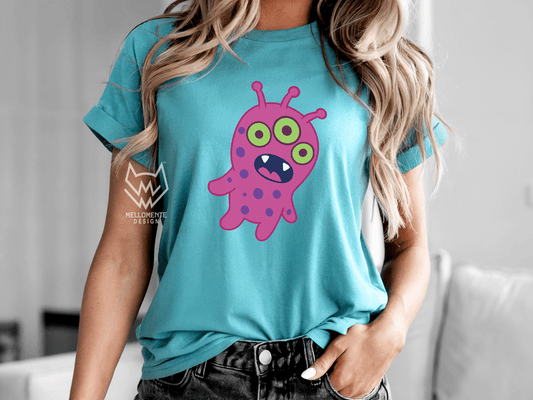 Woman wearing a turquoise shirt featuring a pink alien creature.