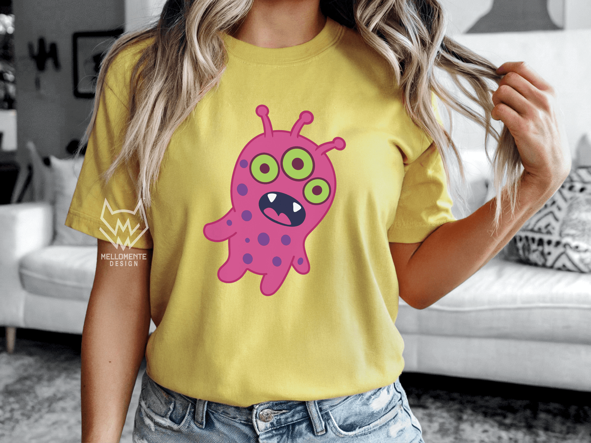 Woman wearing a yellow shirt featuring a pink alien creature.