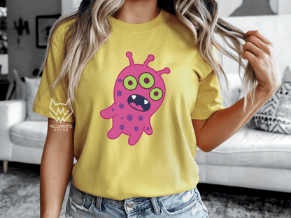 Woman wearing a yellow shirt featuring a pink alien creature.