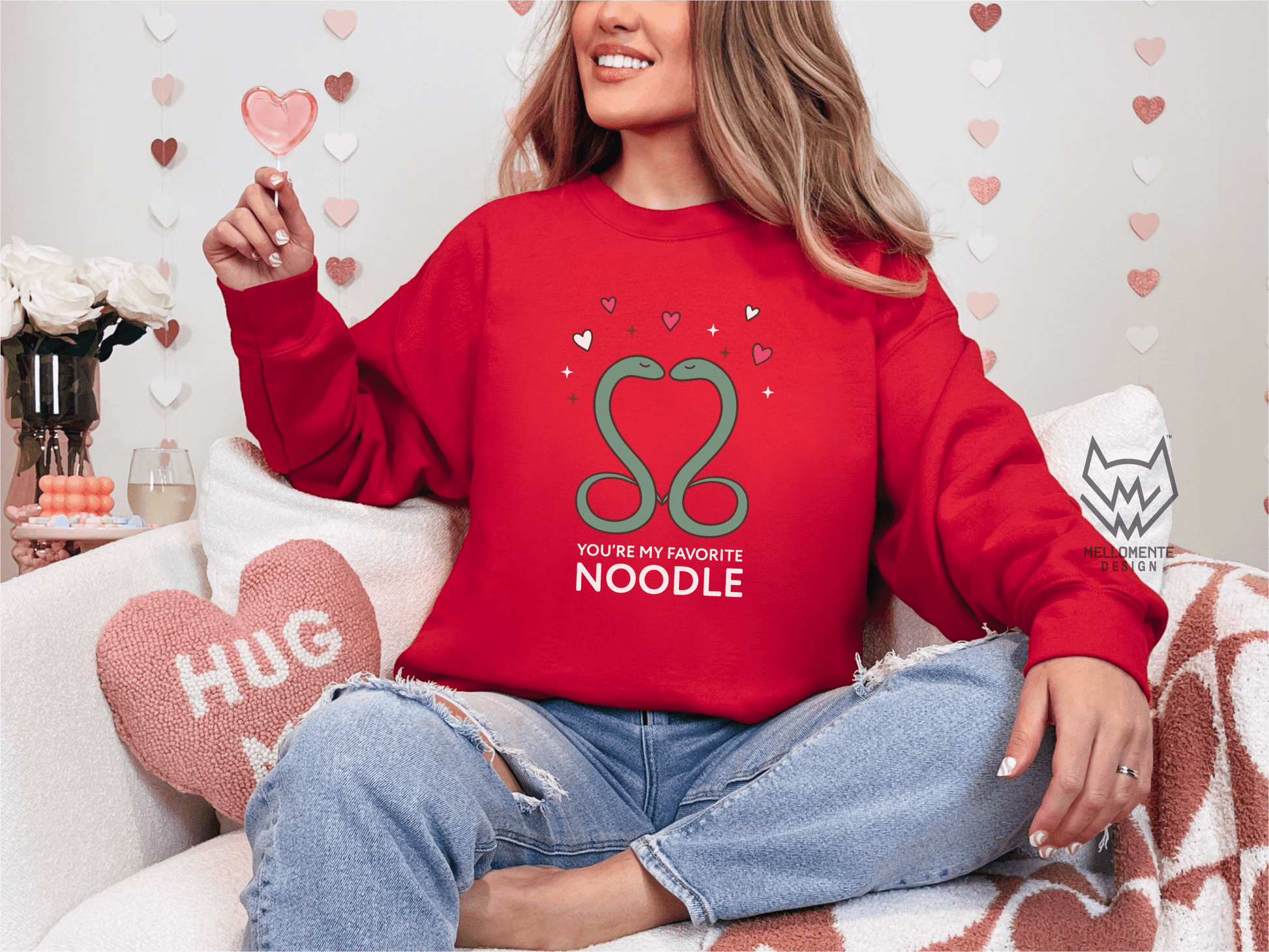 Woman wearing a red sweater featuring a cute valentine themed snake design captioned: "You're my favorite noodle."