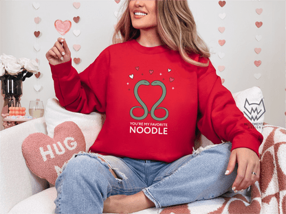 Woman wearing a red sweater featuring a cute valentine themed snake design captioned: "You're my favorite noodle."