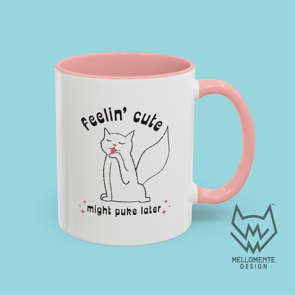 White mug with pink interior featuring a cat illustration and text 'Feelin' cute might puke later' on a solid background.
