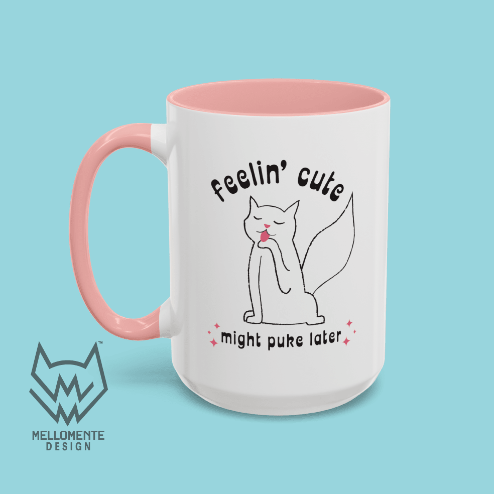 White mug with pink interior featuring a cat illustration and text 'Feelin' cute might puke later' on a solid background.