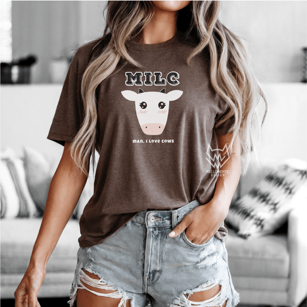 Person wearing a brown t-shirt with a cow graphic and text, standing in a living room.