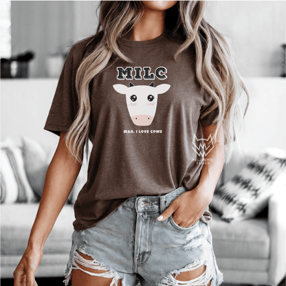 Person wearing a brown t-shirt with a cow graphic and text, standing in a living room.