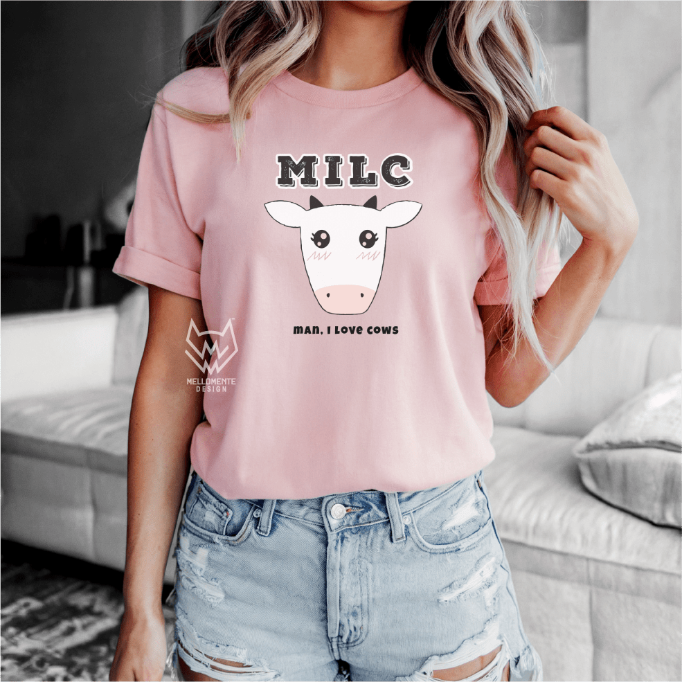 Person wearing a pink t-shirt with a cow graphic and text, standing in a living room.