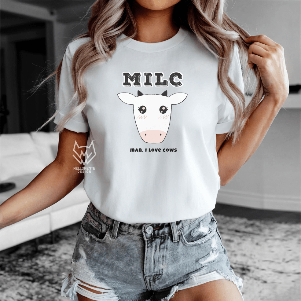 Person wearing a white t-shirt with a cow graphic and text, standing indoors.
