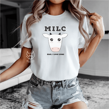 Person wearing a white t-shirt with a cow graphic and text, standing indoors.