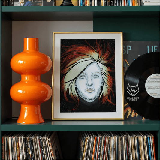 Framed artwork of a face with colorful hair on a shelf with an orange lamp and vinyl records. Framed art shown as display suggestion.